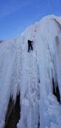 Derek climbs above his white cane that is clipped to a screw in the ice.