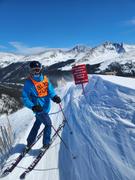 Derek whereing soliman skis at Copper Mountain, above a very steep bowl, standing next to a sign that says "It is a class two offense to enter any area posted as "CLOSED" The terrain was open that day.$1000 max fine"