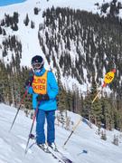 derek standing next to a sign that says "cliff", bundled up, on skis